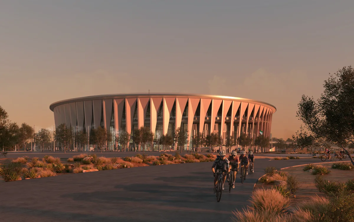 Exterior view of the velodrome at dusk with cyclists on the approach