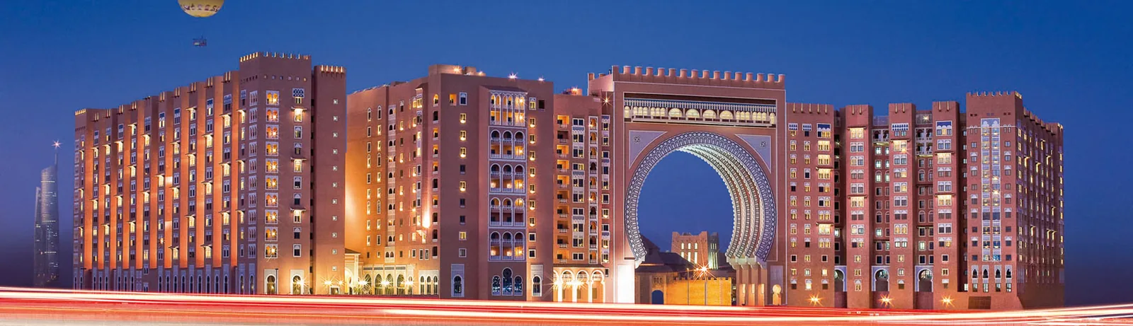 Night panorama of Ibn Battuta Gate, Dubai, with the illuminated central archway